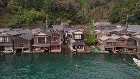 drone en cámara lenta volando sobre casas de botes ine-cho, japón aldea de kyotango mar azul panorámica aérea de las casas tradicionales de madera
