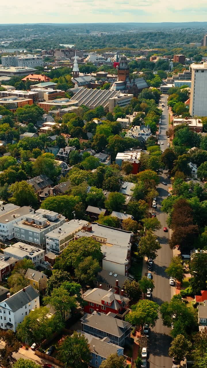 Flying above the sunny panorama of Cambridge, Massachusetts, USA. Beautiful American city with lots of greenery. Top view. Vertical video