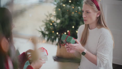 hermanas saludándose mientras intercambian regalos de navidad en casa