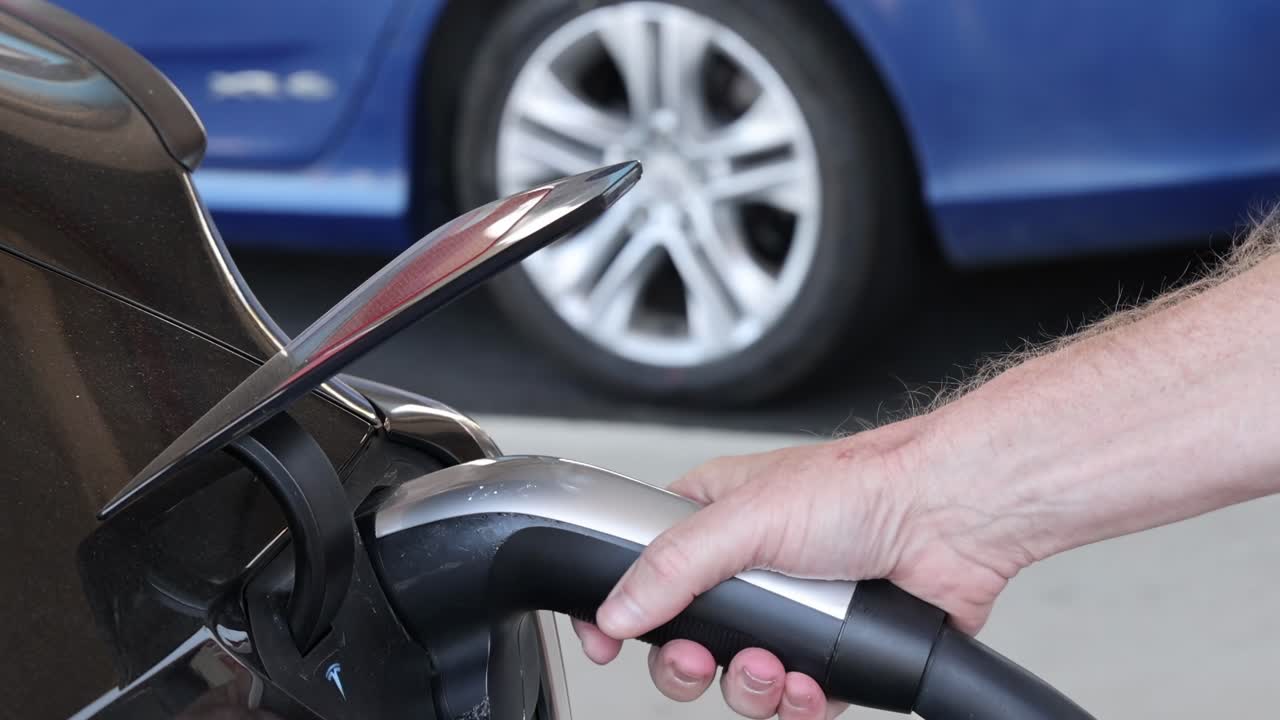 persona conecta el cargador al vehículo eléctrico