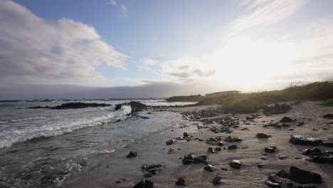 ocean waves breaking on playa de la estacion during sunset in the galapagos. slow motion,  slow pan right