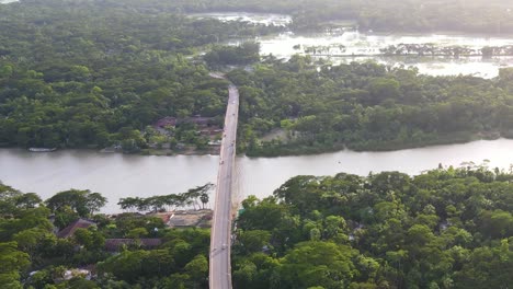 aerial dolly shot of scenic bridge over river surrounded by tropical vegetation, bangladesh