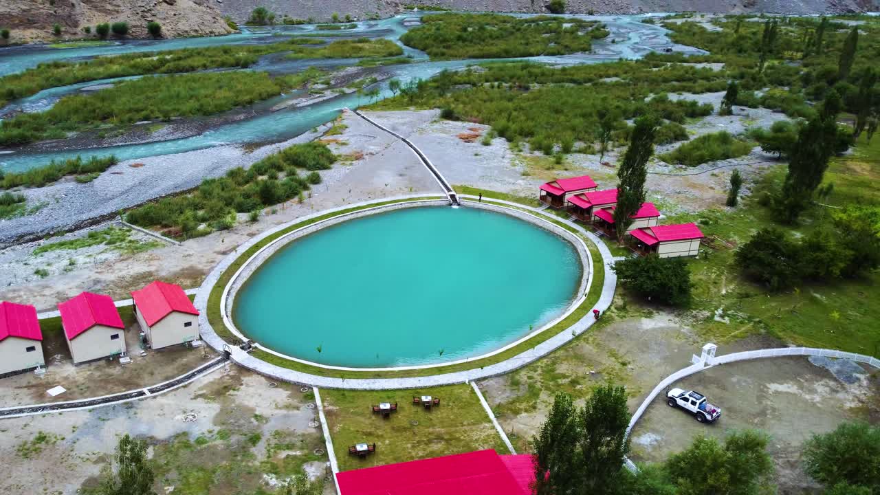 스카르두 (skardu) 의 조용한 소크 계곡을 보여주는 공중 사진, 파키스탄의 호텔과 울창한 초록색으로 둘러싸인 그림 같은 호수를 강조합니다.