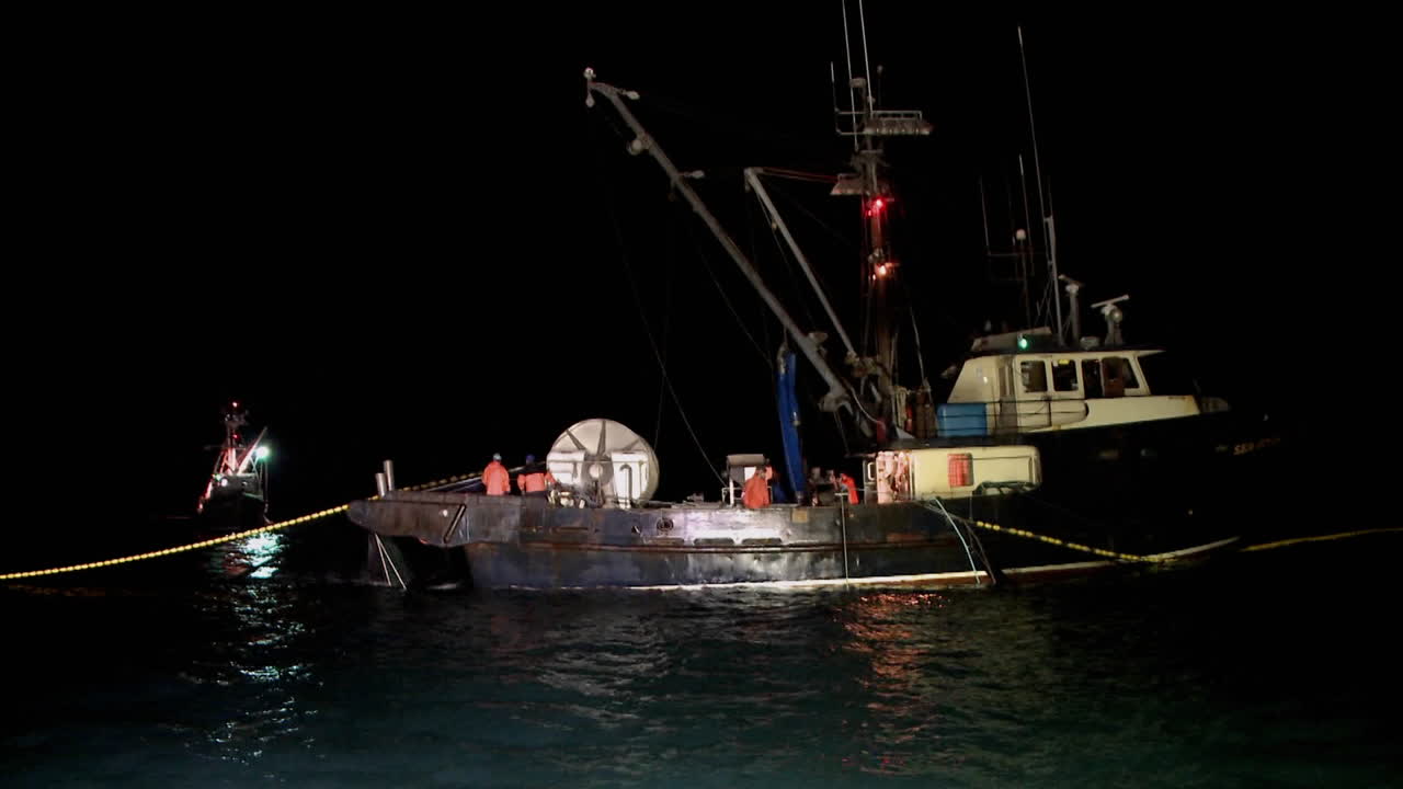 한 무리의 남자들이 작은 어선에서 일한다
