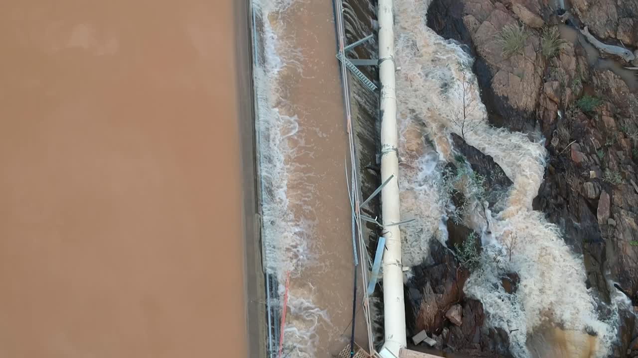 Flood waters cascading over a dam wall from a drone 3