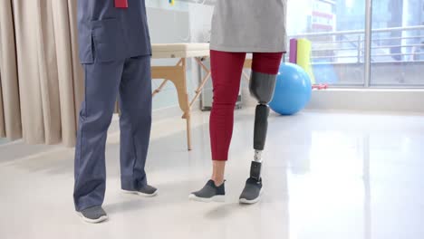 caucasian female physiotherapist and female senior patient with prosthetic leg exercising