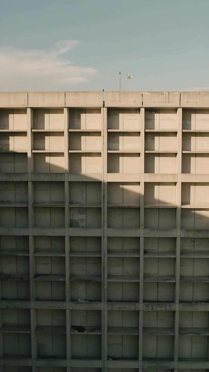 Video vertical: Sol moviendo una sombra diagonal sobre una cuadrícula de paneles en la ciudad cerca de postes en la azotea.