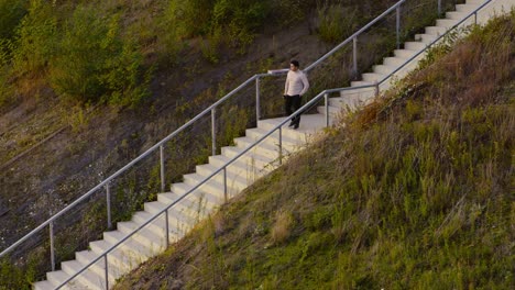 A-young-man-walking-down-the-stairs-of-a-mountain-in-a-beautiful-field