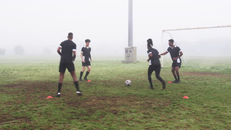 young soccer players practicing on foggy field, focusing on teamwork and skills