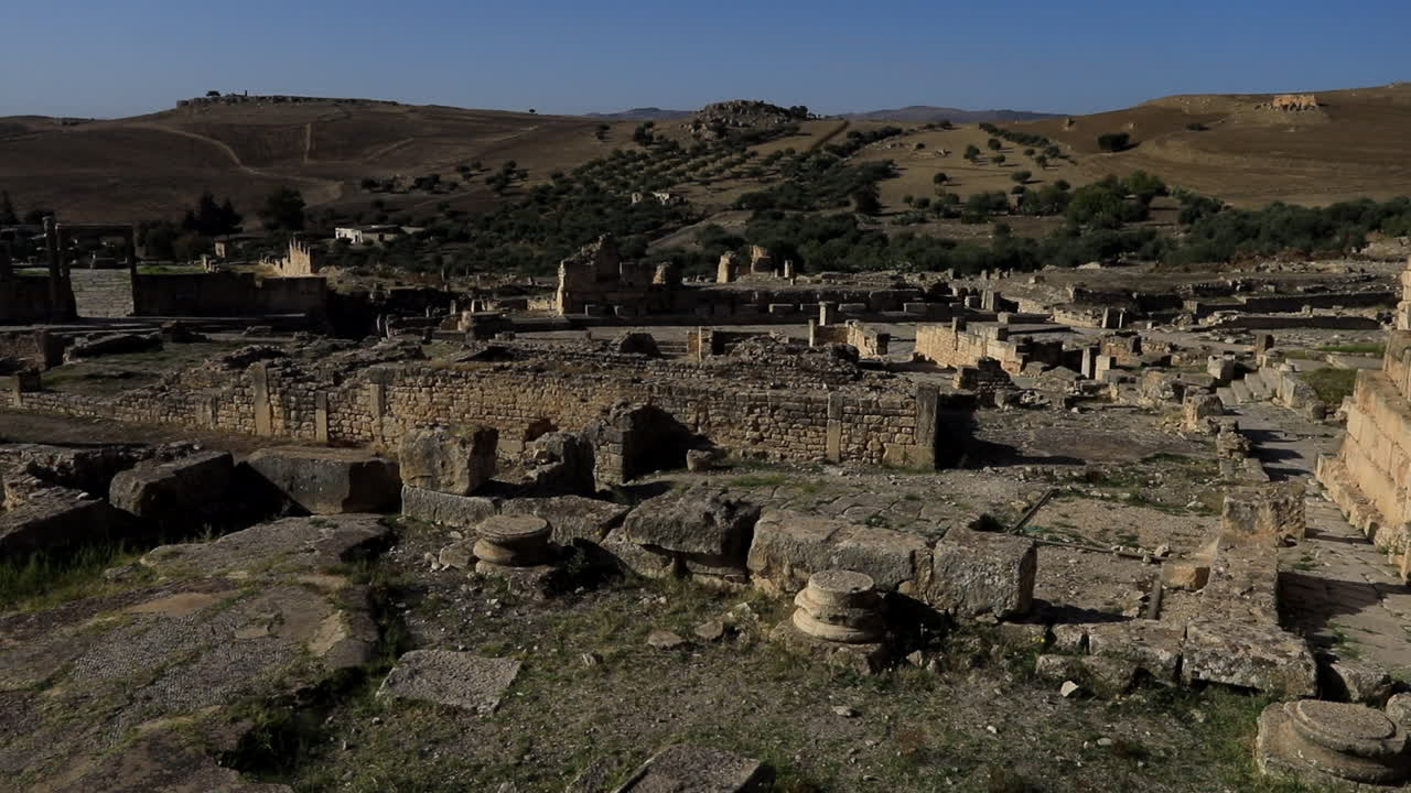 antiguas ruinas romanas en dougga bajo el cielo azul claro, sombras proyectadas sobre el sitio histórico