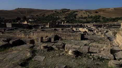 Ancient-Roman-ruins-in-Dougga-under-the-clear-blue-sky,-shadows-cast-over-historic-site