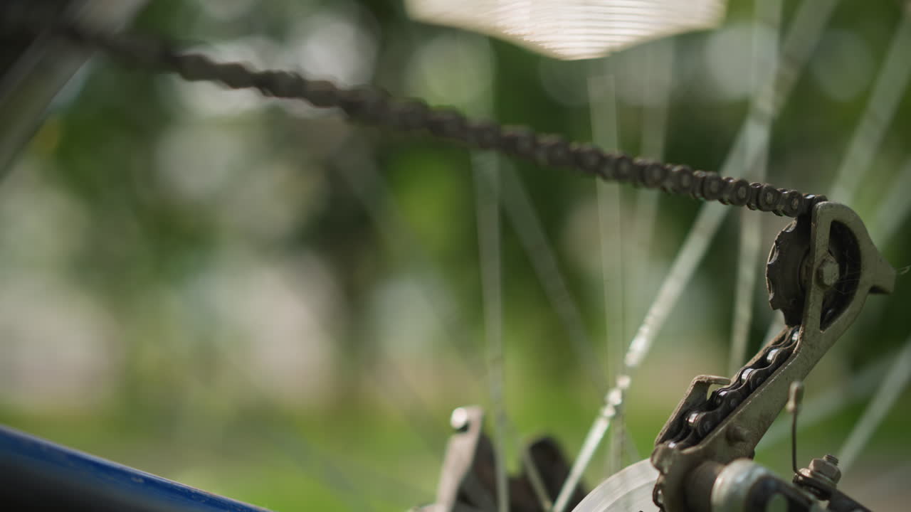 자전거의 뒷바와 기어 시스템의 클로즈업, 체인이 서서히 멈추기 전에 빠르게 회전하는 동안, 초점은 체인과 스피크에 있으며, 배경은 움직임으로 흐릿합니다.