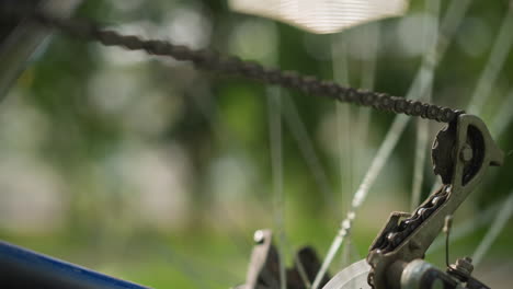 primer plano de la rueda trasera de la bicicleta y el sistema de engranajes mientras la cadena gira rápidamente antes de detenerse gradualmente, el enfoque está en la cadena y los radios, con el fondo borroso por el movimiento