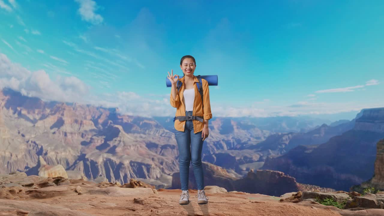 Full Body Of Asian Female Hiker With Mountaineering Backpack Smiling And Showing Okay Gesture To Camera While Traveling At The Top Of Mountain