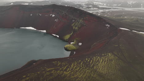 red geological soil volcano with a lake and vegetation iceland aerial