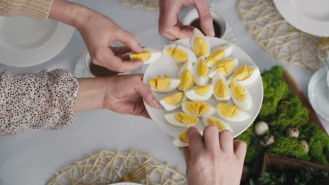 Top-view-of-unrecognizable-family-sharing-with-egg-during-easter-dinner.