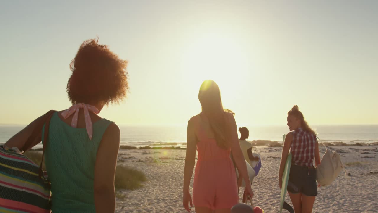 Young adult friends walking on a beach at sunset 4k