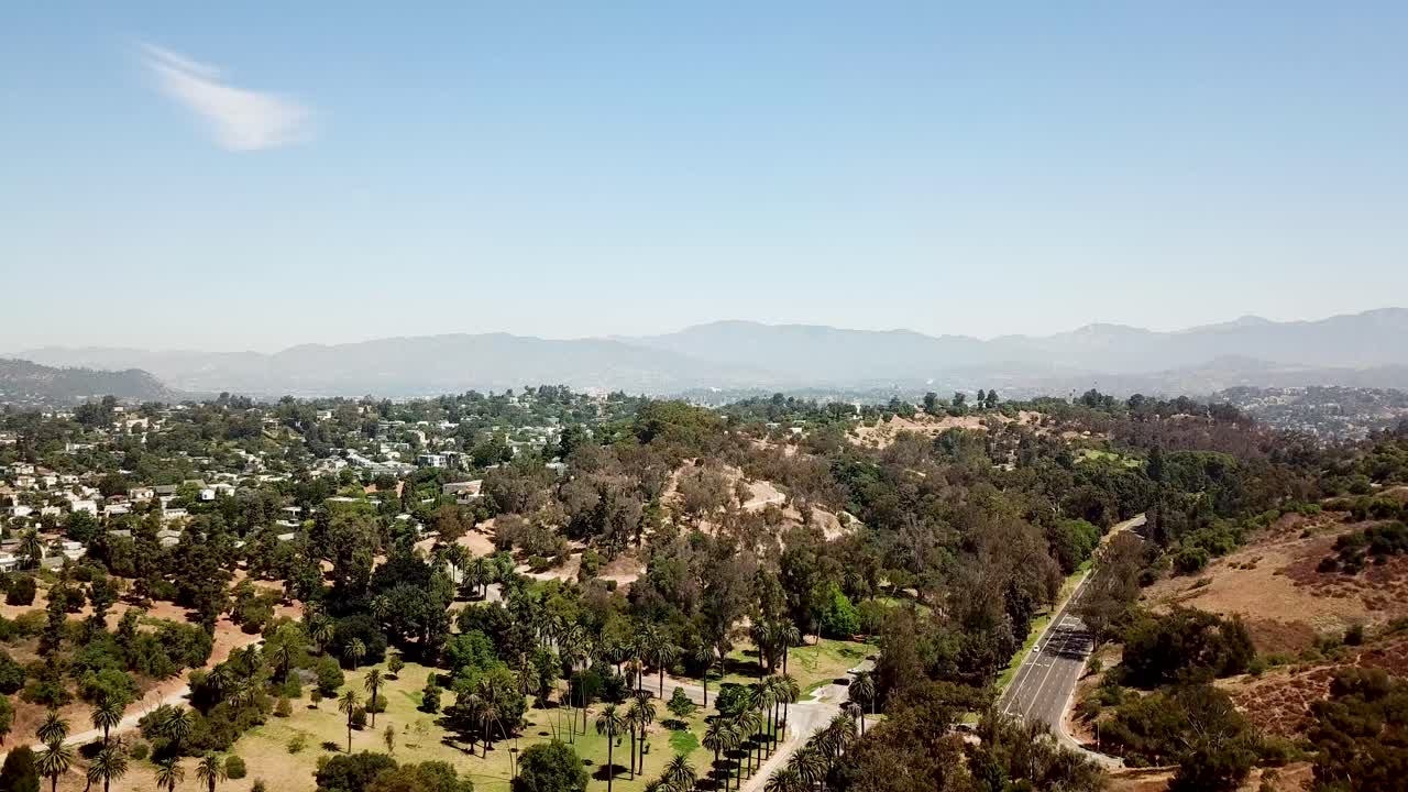 carretera en el centro de los ángeles con el bosque de la nación de ángeles en el fondo durante un día soleado con cielo azul