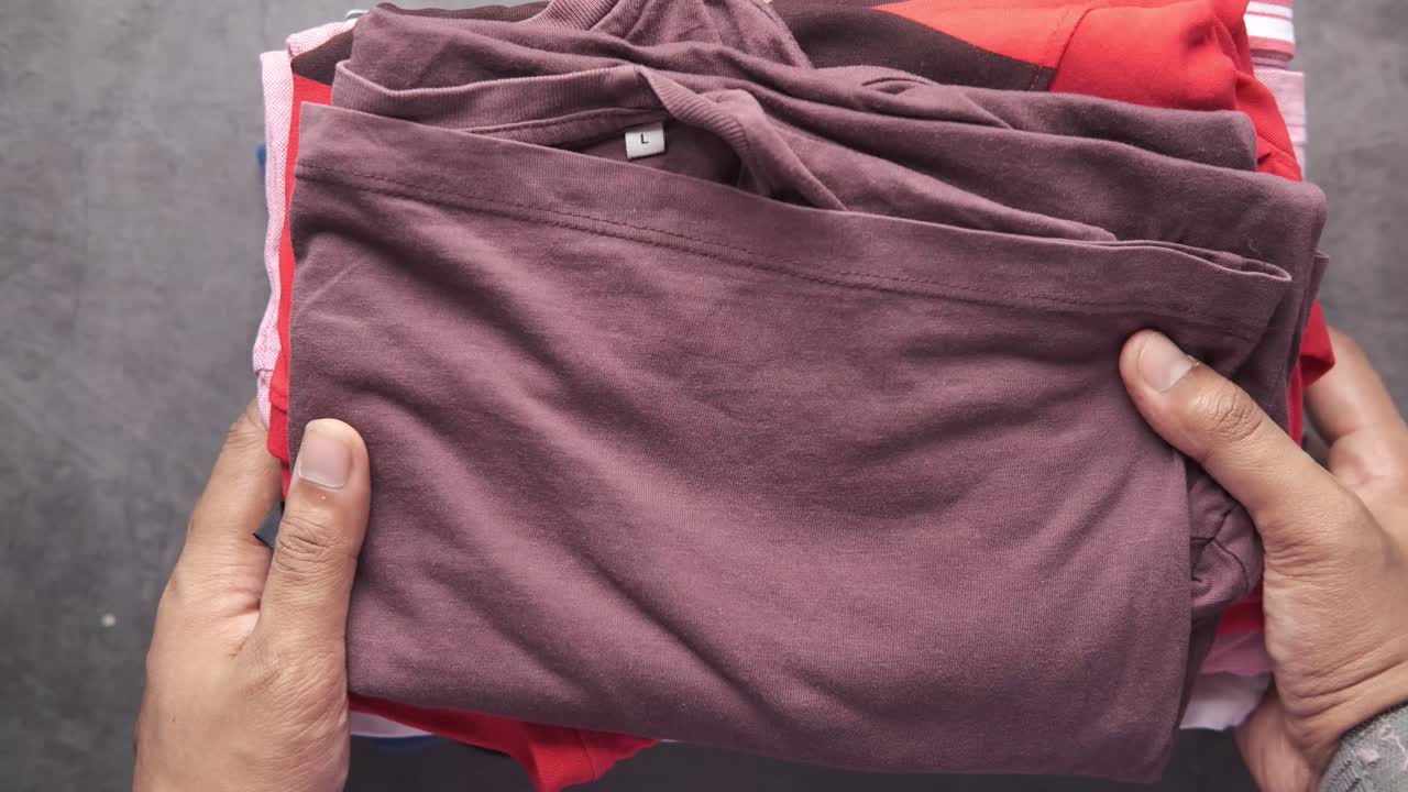 Person holding a stack of folded clothes