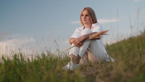 Una-Mujer-Con-Un-Traje-Blanco-Se-Sienta-En-Una-Colina-Admirando-La-Puesta-De-Sol-2