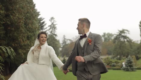 Lovely-newlyweds-caucasian-bride-groom-running-in-park,-holding-hands,-wedding-couple-family