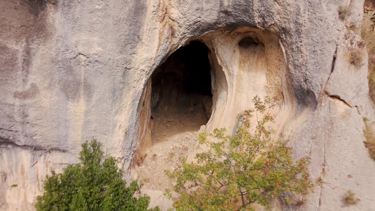 Luftaufnahme eines in eine schroffe Klippe gehauenen Kalksteinhöhleneingangs in Auvergne-Rhône-Alpes, Frankreich
