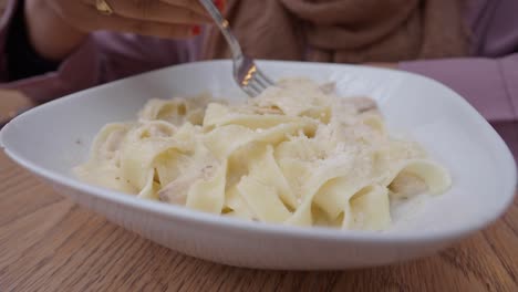 mujer comiendo pollo alfredo pasta