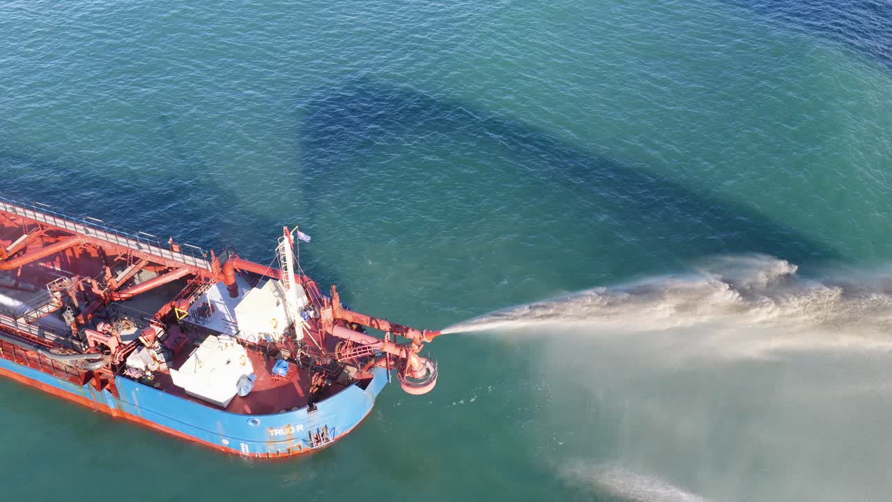 Aerial footage of a dredging ship releasing sediment into the ocean near Gold Coast, Australia. Clear skies and calm waters