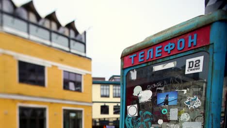 vintage telephone booth decorated with stickers in a cityscape