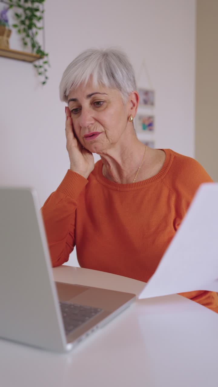 Stressed Senior Woman Struggling with Papers and Laptop