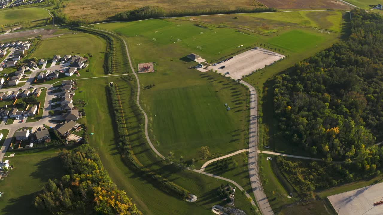 vista panorámica de un hermoso parque de fútbol verde y exuberante con senderos para caminar y estructuras de juego cercanas