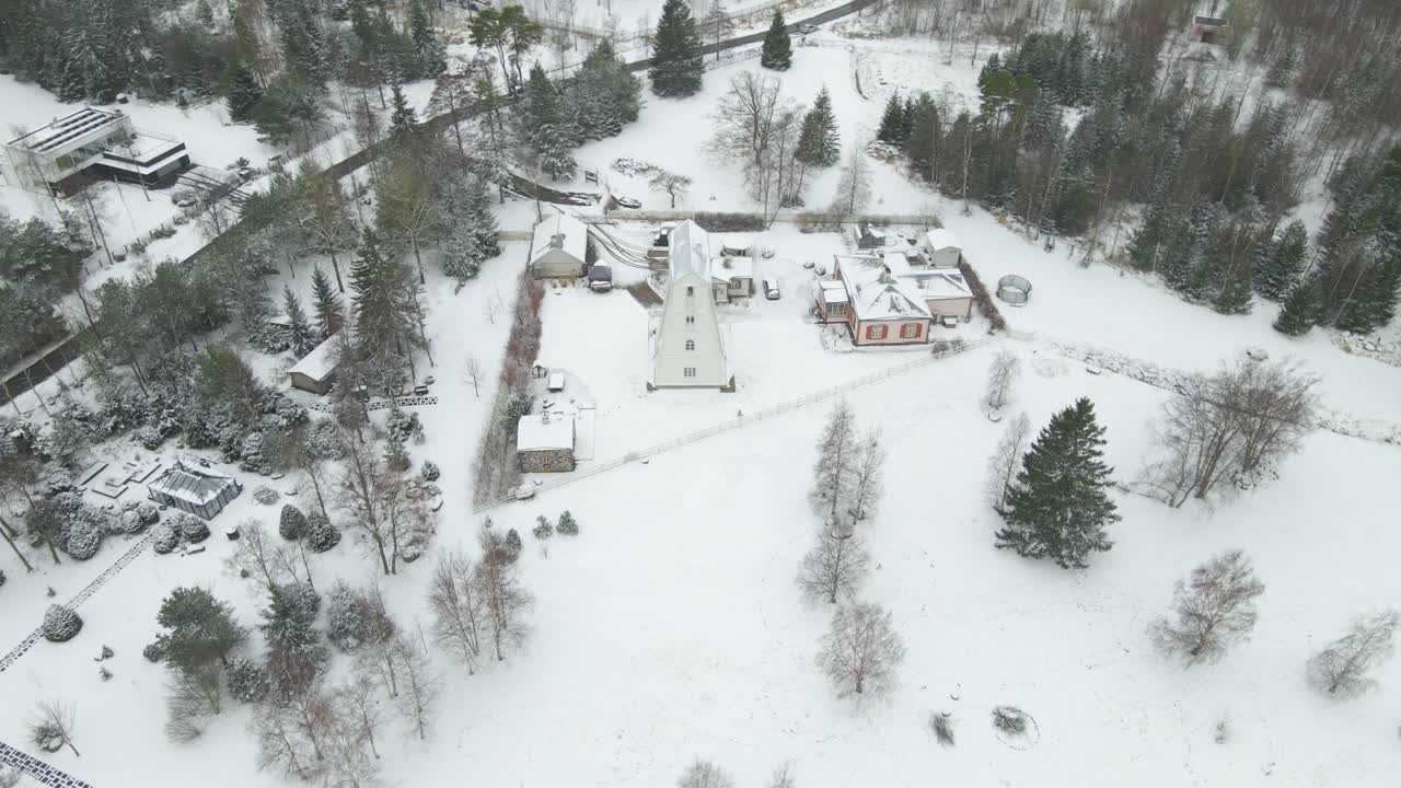 Drone view of coastal town with wooden houses and lighthouse along the cliff bank coastline. Winter village next to, facing the sea. Aerial perspective changing landscape, cliff overlooking the sea