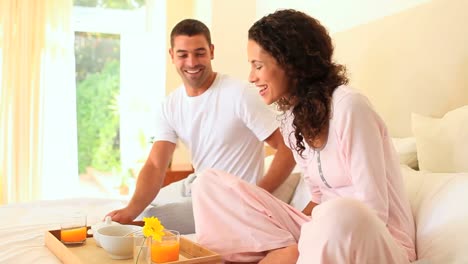 man bringing breakfast in bed to his wife