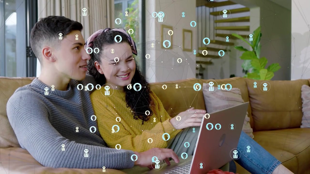 Couple sitting on mustard-colored sofa in modern living room, sharing silver laptop with overlay
