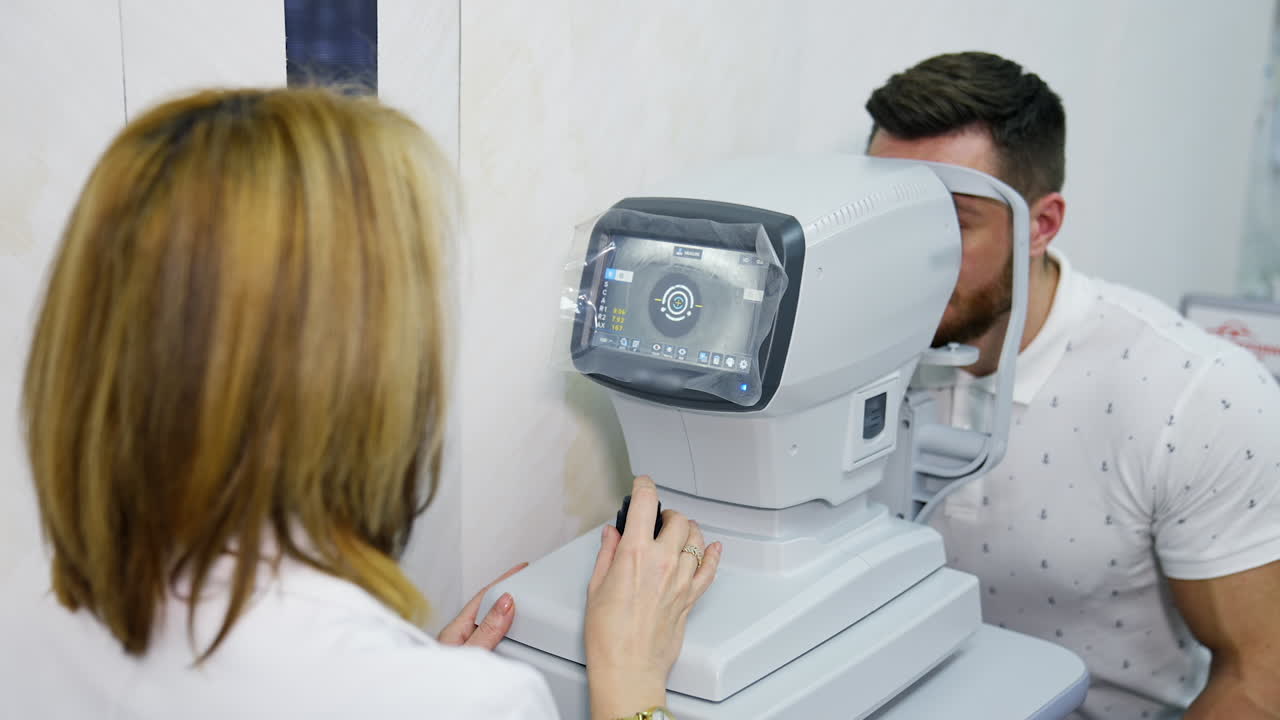 Oculist doctor works in a ophthalmology clinic. Woman specialist uses an apparatus for biomicroscopy of the eye to check the sight of an adult man.