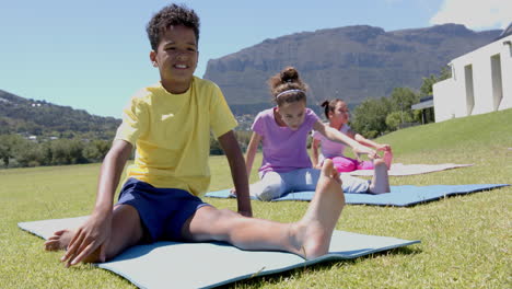 biracial boy and girls practice yoga outdoors, with mountains in the background, in school