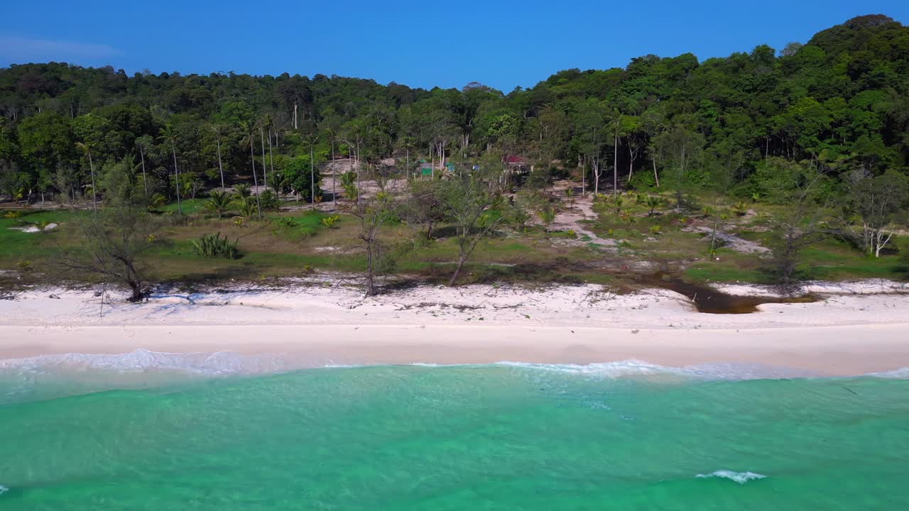 Tropical landscape showing turquoise sea washing white sand beach and green rainforest covering Koh Rong island in Cambodia. Magic aerial view flight dolly left drone