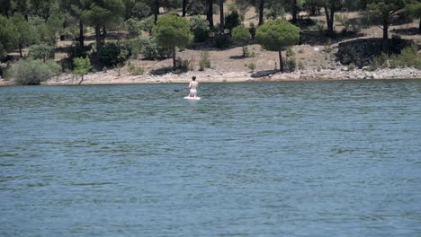 Frau-Auf-Knien-Paddeln-Auf-Dem-Stand-Up-Paddle-Board-Am-See,-Pantano-De-San-Juan,-Madrid