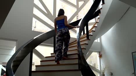 a woman climbs the stairs to the top floor of the house