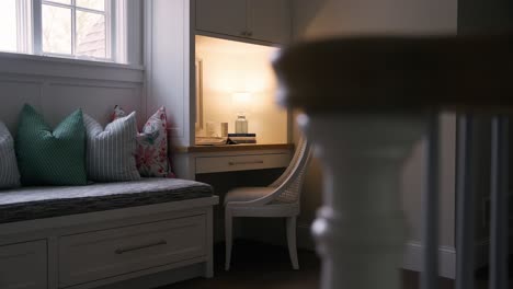 Cozy-desk-with-lamp,-books,-photo,-and-bench-by-windows