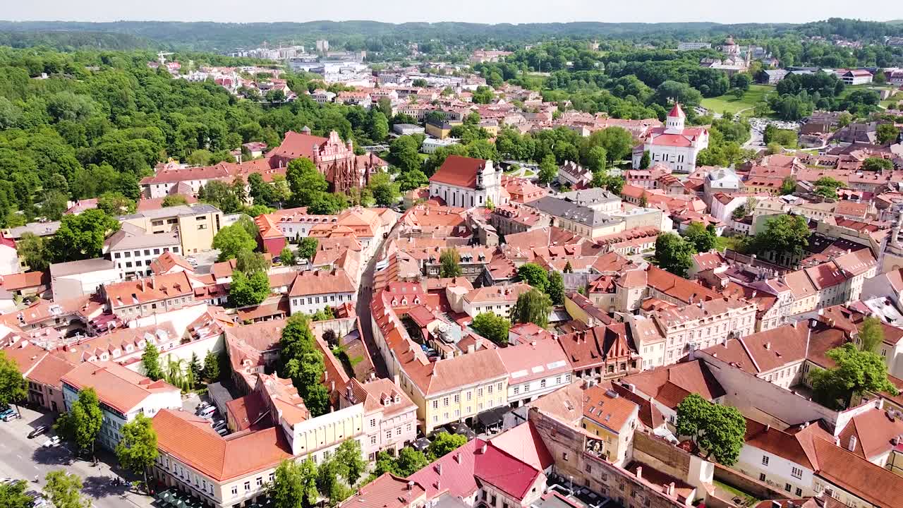 Czerwono-zielone barwy Starego Miasta w Wilnie w słoneczny dzień, ujęcie z drona oddalające się.