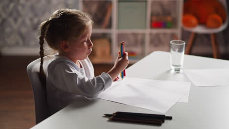 Little-artist-gathers-crayons-in-bunch-to-draw-at-table