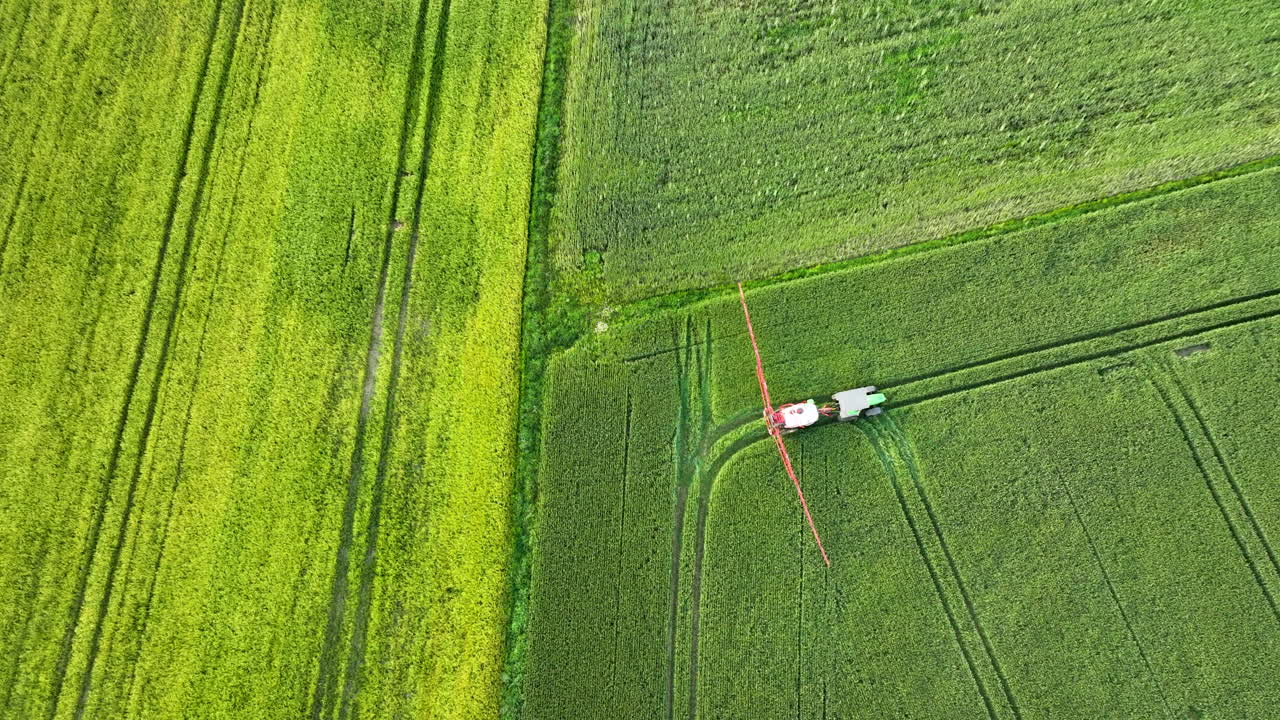 Aerial view of a tractor spraying crops in a green agricultural field