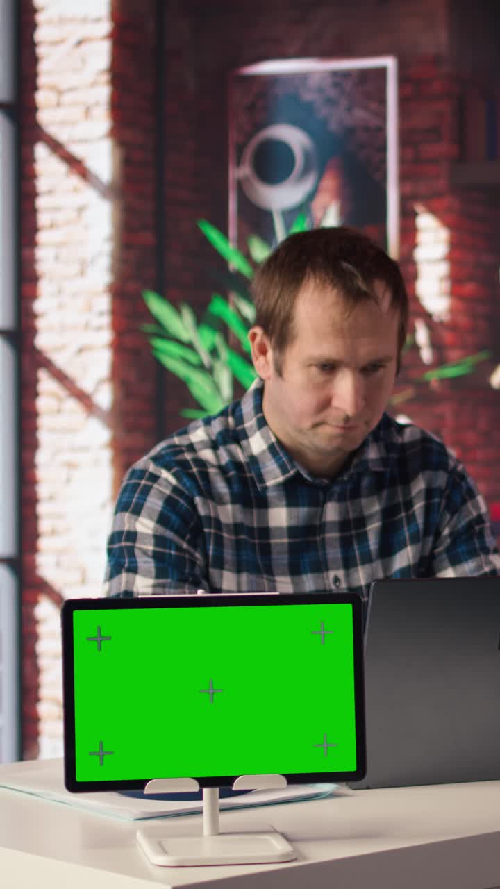 Vertical video Mockup tablet next to worker listening music, analyzing data on laptop