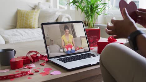 Fröhliche-Gemischtrassige-Frau,-Die-Ein-Geschenk-öffnet-Und-Einen-Videoanruf-Zum-Valentinstag-Auf-Dem-Laptop-Tätigt