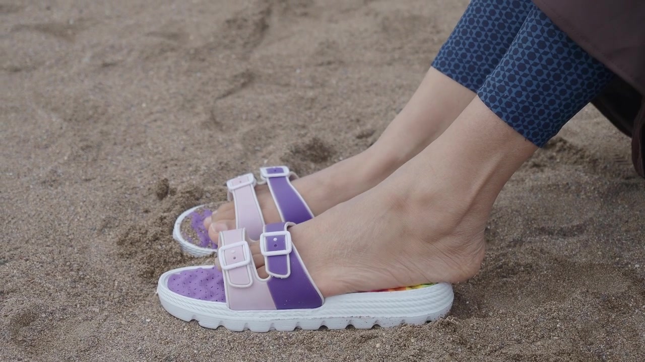 Pessoa Usando Sandálias Roxas Sentada na Praia de Areia