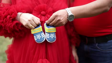 couple posing for maternity photoshoot with baby shoes