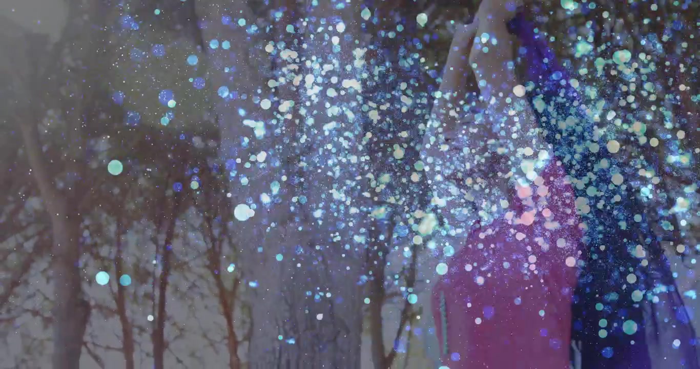 Mulher posando em um bosque, levantando um cachecol roxo, iniciando o crescimento de uma sobreposição de glitter para uma sessão de fotos de moda.
