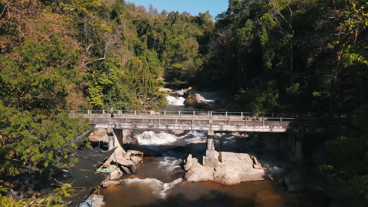 아름다운 태국 자연 속에서 그녀의 행복 축 주위를 돌면서 매클랑 폭포 위의 산책로를 걷는 관광객