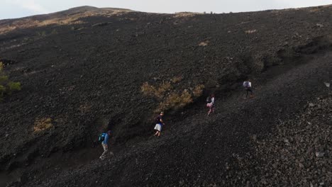 cuatro turistas, dos hombres y dos mujeres, caminan por el escarpado sendero volcánico que conduce a la cumbre del cráter del volcán paricutin en michoacán, méxico.